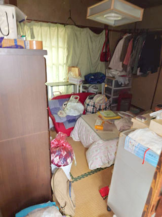 寝具と衣類が残った和室